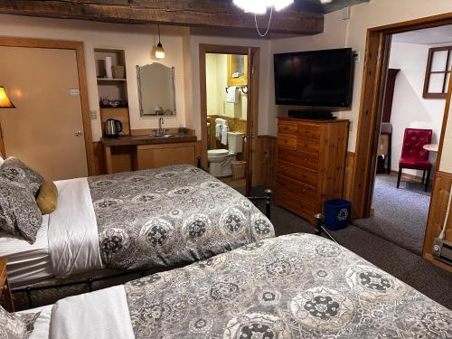 a bedroom with two beds and a flat screen tv at Chewuch Inn & Cabins in Winthrop