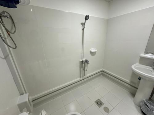 a white bathroom with a shower and a toilet at International Abu-Dhabi Hostel Villa in Abu Dhabi