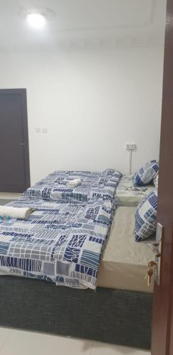 a bed with blue and white sheets and pillows at International Abu-Dhabi Hostel Villa in Abu Dhabi