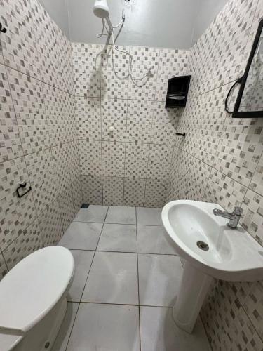 a white bathroom with a toilet and a sink at Spacious and comfortable apartment in Oiapoque