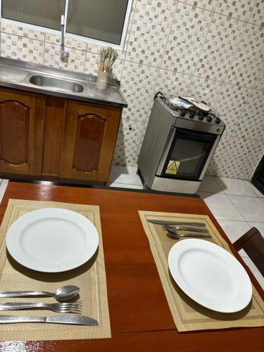 a kitchen with two white plates on a wooden table at Spacious and comfortable apartment in Oiapoque