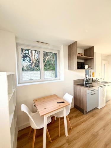 une petite cuisine avec une table et des chaises en bois dans l'établissement Appartements meublés Brest Gay Lussac, à Brest
