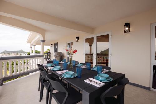 a black table with blue plates and chairs on a balcony at Sauna Pool Game Room Bliss in Rodney Bay Village