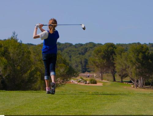 a woman hitting a golf ball with a club at Els Vents OM IN WHITE, Refugio Zen en Son Parc, tranquilidad a 5 minutos de la playa in Son Parc