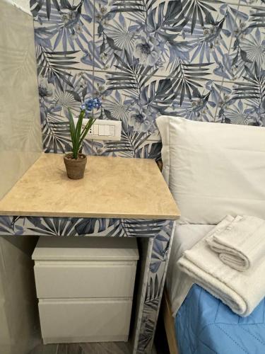 a table with a plant on it next to a bed at LUXOR ECO ROMA CASA E APPARTAMENTO PER VACANZE IN CENTRO Piazza Bologna, Colosseo, Piazza di Spagna, Vaticano, San Pietro, Sapienza, Fontana di Trevi, Piazza Navona, Trastevere, Tiburtina, Termini, Aeroporto in Rome