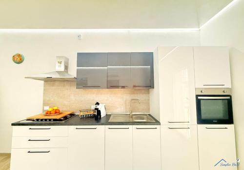 a white kitchen with white cabinets and a sink at Sicilia bedda in Custonaci