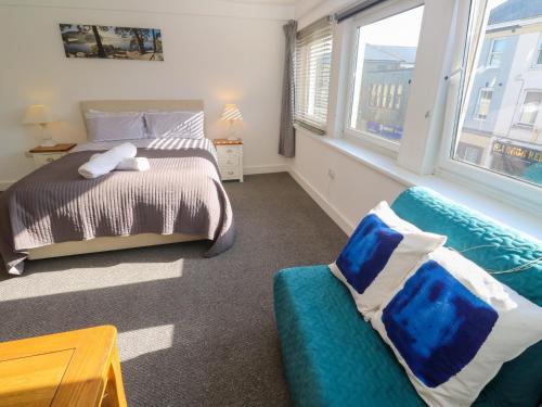 a bedroom with a bed and a couch and windows at Flat 1 in Penzance