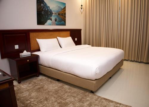 a bedroom with a large bed and a night stand at الموج للشقق الفندقية in Falaj al Qabāʼil