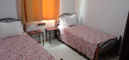 a bedroom with two beds with red and white sheets at Hotel Bab Boujloud in Fès
