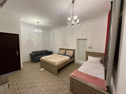 a bedroom with two beds and a couch and a chandelier at International Abu Dhabi Hostel in Abu Dhabi