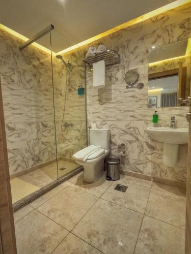 a bathroom with a shower and a toilet and a sink at Grand Season Hotel in Aqaba