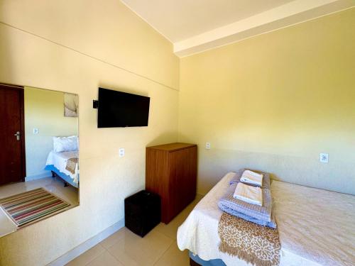 a bedroom with a bed and a tv on the wall at Pousada Casa de Maitreya in Alto Paraíso de Goiás