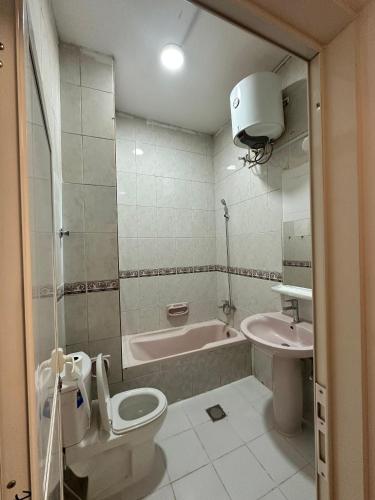 a bathroom with a toilet and a tub and a sink at International Abu Dhabi Hostel in Abu Dhabi