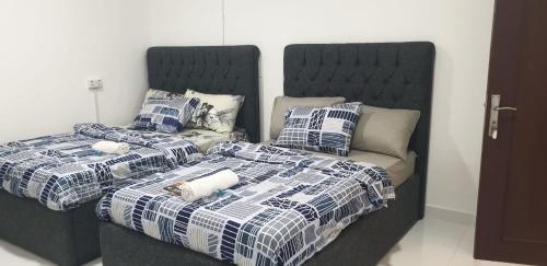 two beds with blue and white blankets and pillows at International Abu Dhabi Hostel in Abu Dhabi