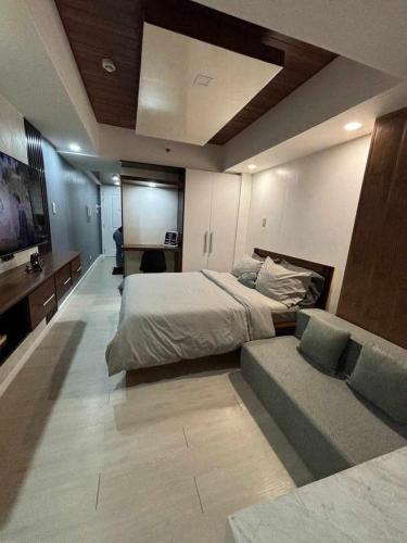a large bedroom with a bed and a couch at 22nd-Floor Spacious Studio with Sunrise & Pool Views, Hi-Speed WiFi & Working Space, Netflix, Disney, Kitchen, Wide Balcony in San Fernando