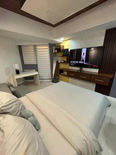 a bedroom with a large bed and a flat screen tv at 22nd-Floor Spacious Studio with Sunrise & Pool Views, Hi-Speed WiFi & Working Space, Netflix, Disney, Kitchen, Wide Balcony in San Fernando