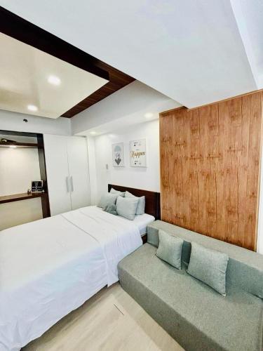 a bedroom with a large white bed and a couch at 22nd-Floor Spacious Studio with Sunrise & Pool Views, Hi-Speed WiFi & Working Space, Netflix, Disney, Kitchen, Wide Balcony in San Fernando