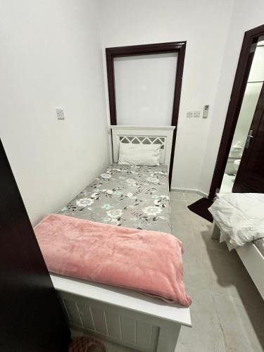 a small bed in a room with a mirror at International Abu Dhabi Hostel in Abu Dhabi