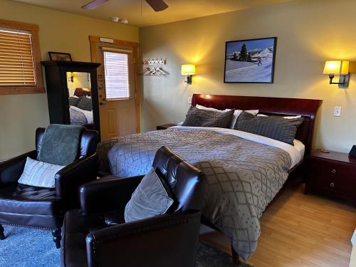 a bedroom with a bed and two chairs at Chewuch Inn & Cabins in Winthrop
