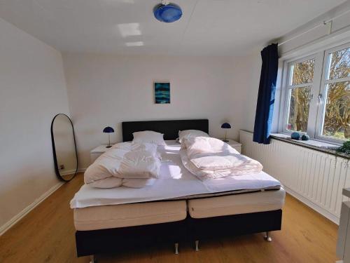 a bedroom with a bed with white sheets and pillows at 4 star holiday home in Løkken in Løgsted