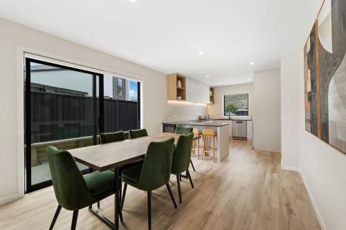 a dining room and kitchen with a table and green chairs at Stirling Woods Retreat in Cromwell