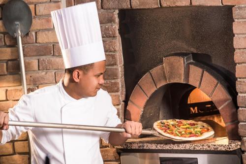 a chef putting a pizza into an oven at Novotel Abu Dhabi Gate in Abu Dhabi