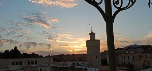 a building with a clock tower in front of a sunset at Hotel Bab Boujloud in Fès