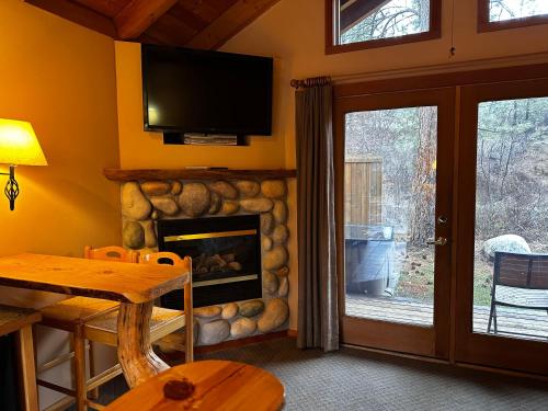 a living room with a fireplace and a tv at Chewuch Inn & Cabins in Winthrop