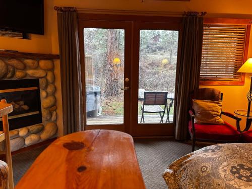 a living room with a wooden table and a fireplace at Chewuch Inn & Cabins in Winthrop