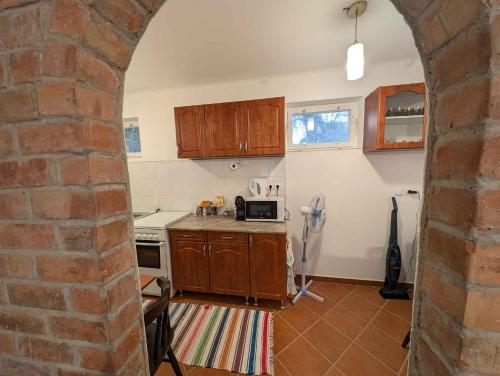 a kitchen with wooden cabinets and a brick wall at Holiday home in Kötcse - Südtransdanubien 53934 in Kötcse