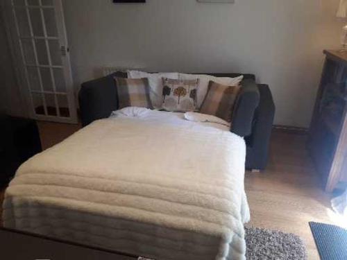 a bed with a white blanket on it in a room at The Garden Flat in Windermere