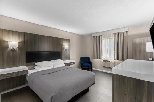 a hotel room with a bed and a blue chair at Quality Inn Oskaloosa in Oskaloosa