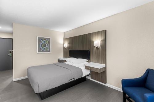 a hotel room with a bed and a blue chair at Quality Inn Oskaloosa in Oskaloosa