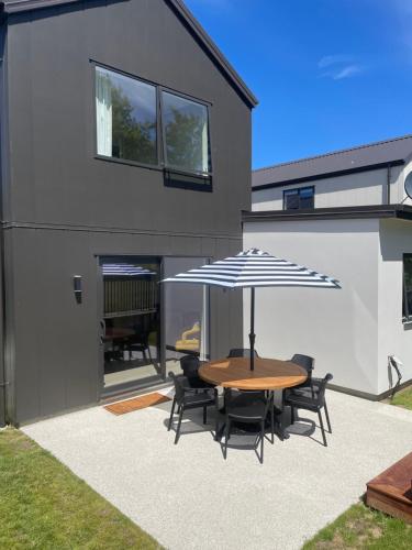 a patio with a table and chairs and an umbrella at Stirling Woods Retreat in Cromwell