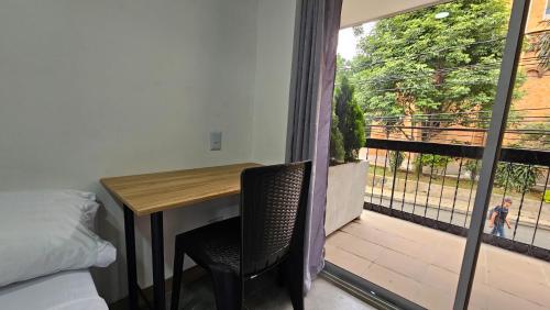 a bedroom with a table and a balcony with a view at Komfort House Premium in Medellín