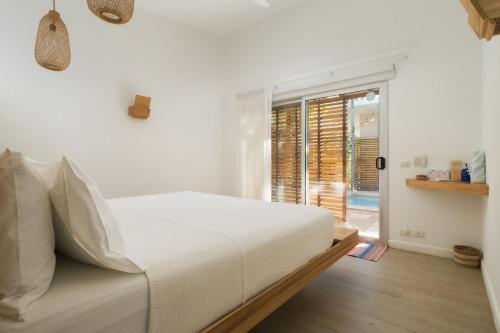 - une chambre blanche avec un lit et une porte coulissante en verre dans l'établissement BOHO Tamarindo, à Tamarindo