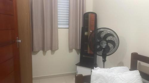 イタニャエンにあるcasa 3, espaço inteiroのベッド1台、窓際のファンが備わる客室です。