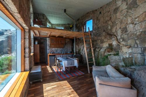 a living room with a stone wall and a ladder at Rustic Mountain Shelter Pure Nature in Las Rabonas