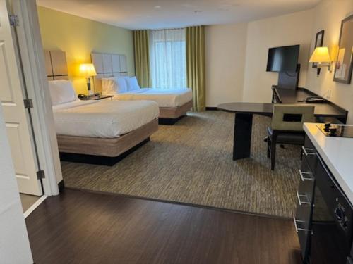 a hotel room with two beds and a desk at Candlewood Suites Eugene Springfield by IHG in Eugene
