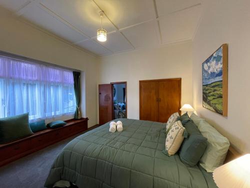 a bedroom with a green bed and a window at Classic 4 bedrooms house opposite Waikato Hospital in Hamilton