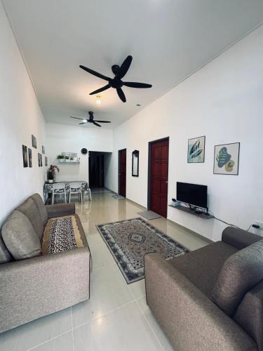 a living room with two couches and a ceiling fan at Homestay CikguMa 1 - WiFi in Kota Bharu
