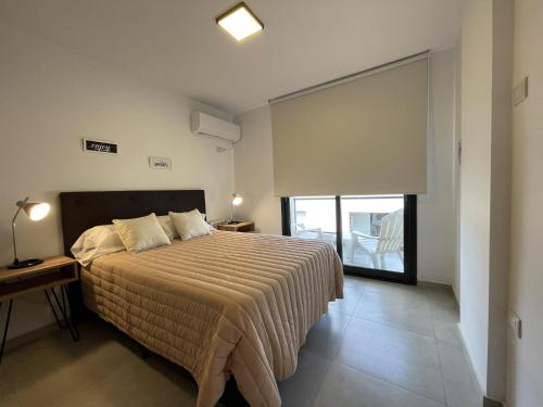 a bedroom with a bed and a large window at Depto Paseo Quattro in Villa Carlos Paz
