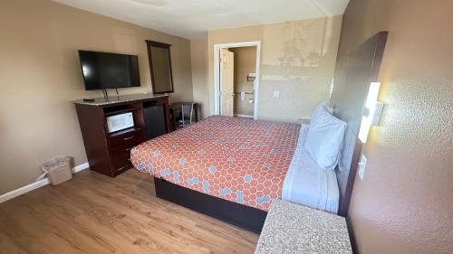 a small hotel room with a bed and a flat screen tv at Valley Inn in Watsonville
