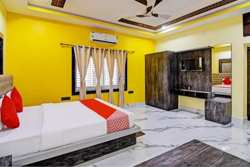 a yellow bedroom with a bed and a kitchen at Hotel O SRI SAI PALACE in Bārang