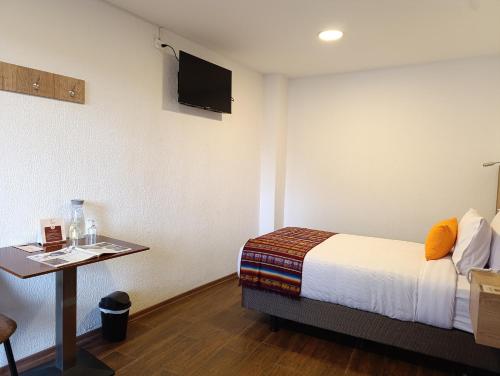 a room with a bed and a table and a tv at Casona Tobar Hotel in Quito