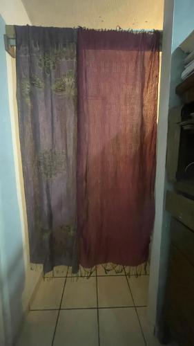 a red curtain in a bathroom with a tile floor at Cativa77 in Hermosillo