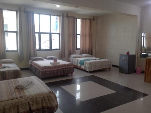 a room with three beds in a room with windows at Casa Nativa Iquitos in Iquitos