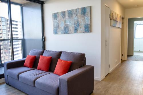 a blue couch with two red pillows in a living room at Park Avenue - IKON Glen Waverley in Glen Waverley