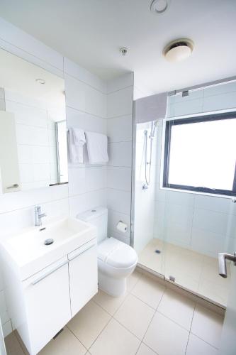 a white bathroom with a toilet and a sink at Park Avenue - IKON Glen Waverley in Glen Waverley