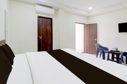 a bedroom with a bed and a table and chairs at Super Hotel O Ramavarapadu Near PVR Icon in Vijayawada
